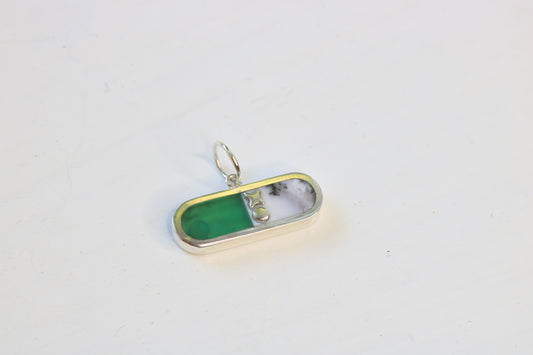pill shaped sterling silver charm inlaid with chrysoprase and merlinite and an xo descriptor