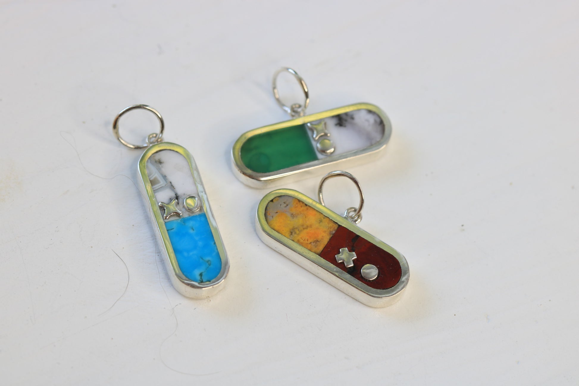 three I love drugs charms inlaid with turquoise and merlinite, chrysoprase and merlinite, or bumblebee jasper and dot's plume.  All charms are sterling silver and include xo letter descriptor.