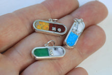 Load image into Gallery viewer, Three sterling silver charms with stone inlay held in a hand with white background. 
