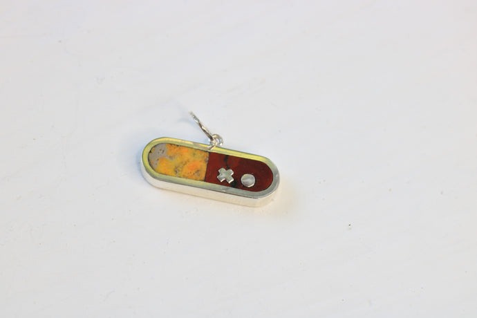 sterling silver pill shaped charm inlaid with bumblebee jasper and dot's plume on a white background