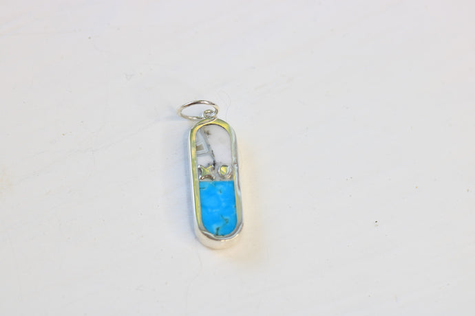 capsule shaped charm with an xo letter descriptor in sterling silver and inlaid with turquoise and merlinite on a white background