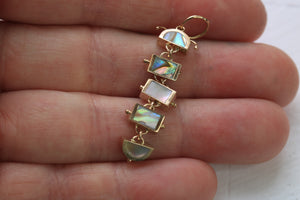 14k gold five piece caterpillar charm inlaid with abalone laying in hand