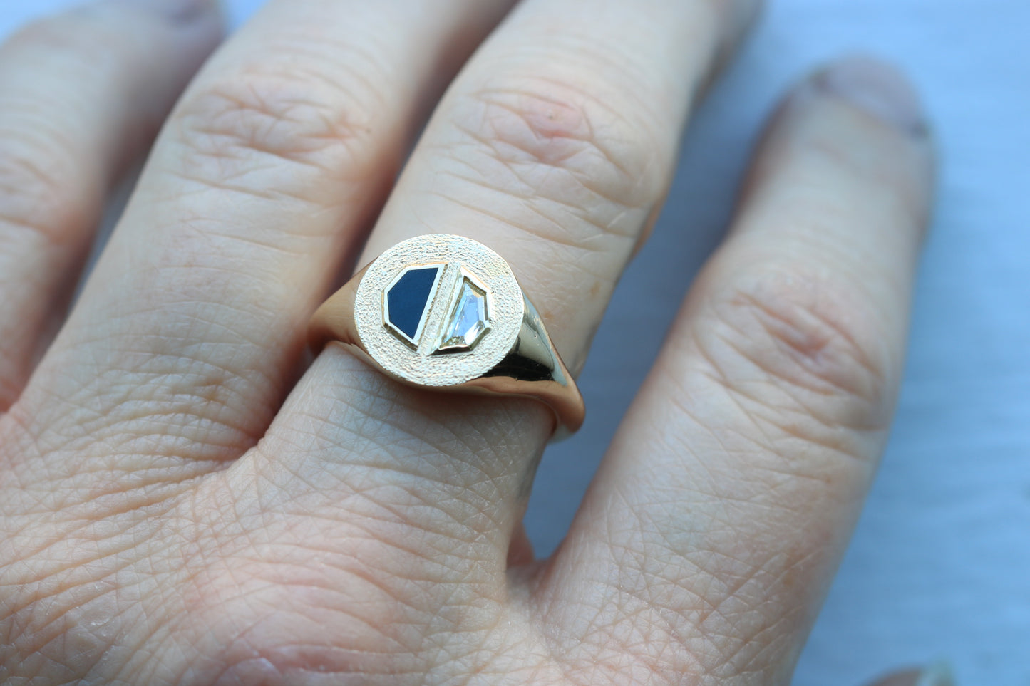 14k gold ring on hand signet style with a half octagon black stone inlay and half octagon natural diamond.