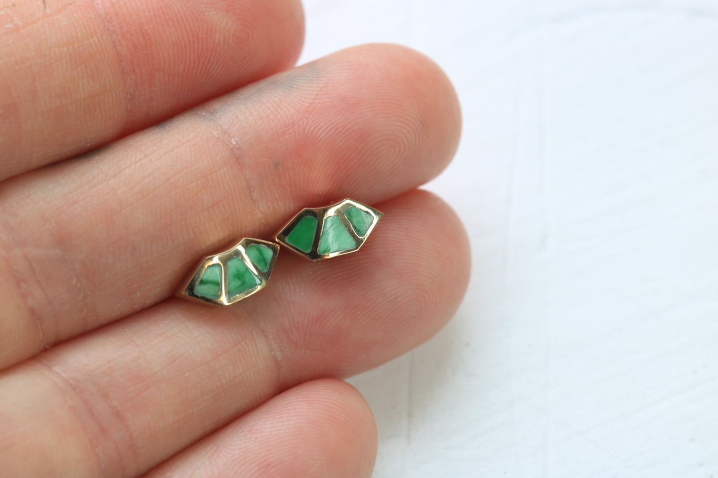 14k yellow gold fan studs with  variscite inlay in hand on white background