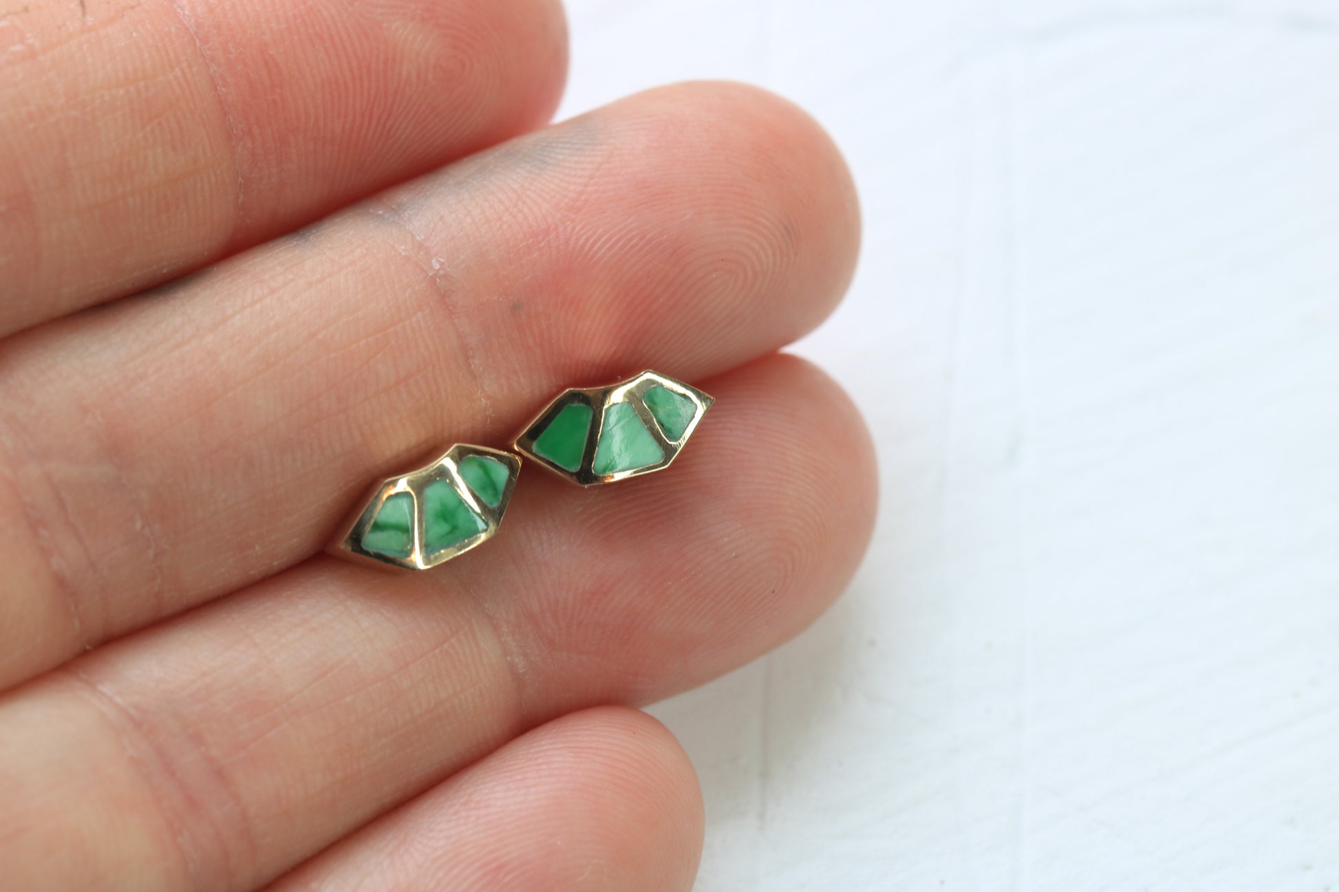14k yellow gold fan studs with  variscite inlay in hand on white background