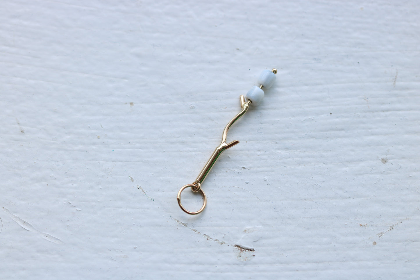 14k yellow gold branch with two mother of pearl marshmallow beads.
