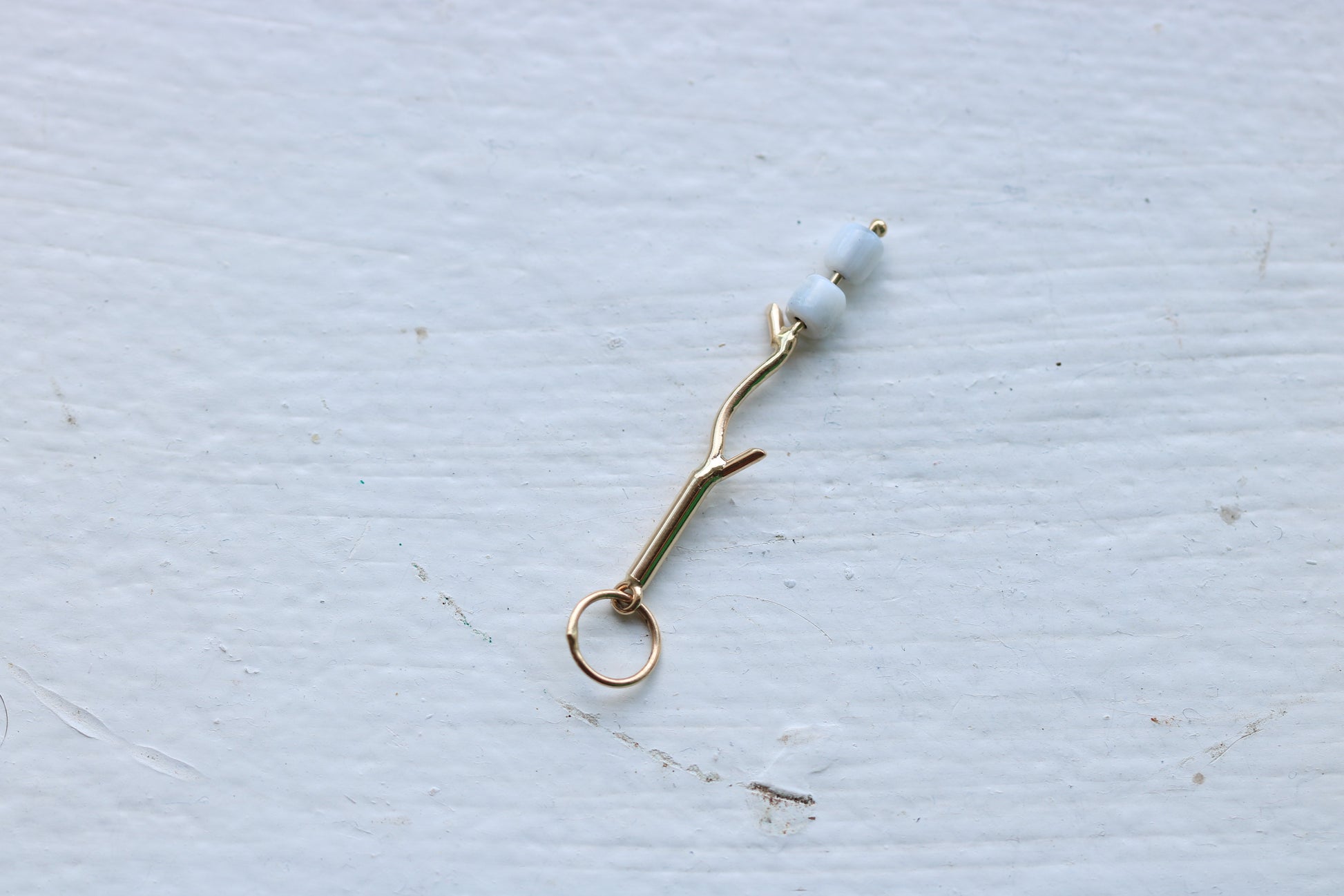 14k yellow gold branch with two mother of pearl marshmallow beads.
