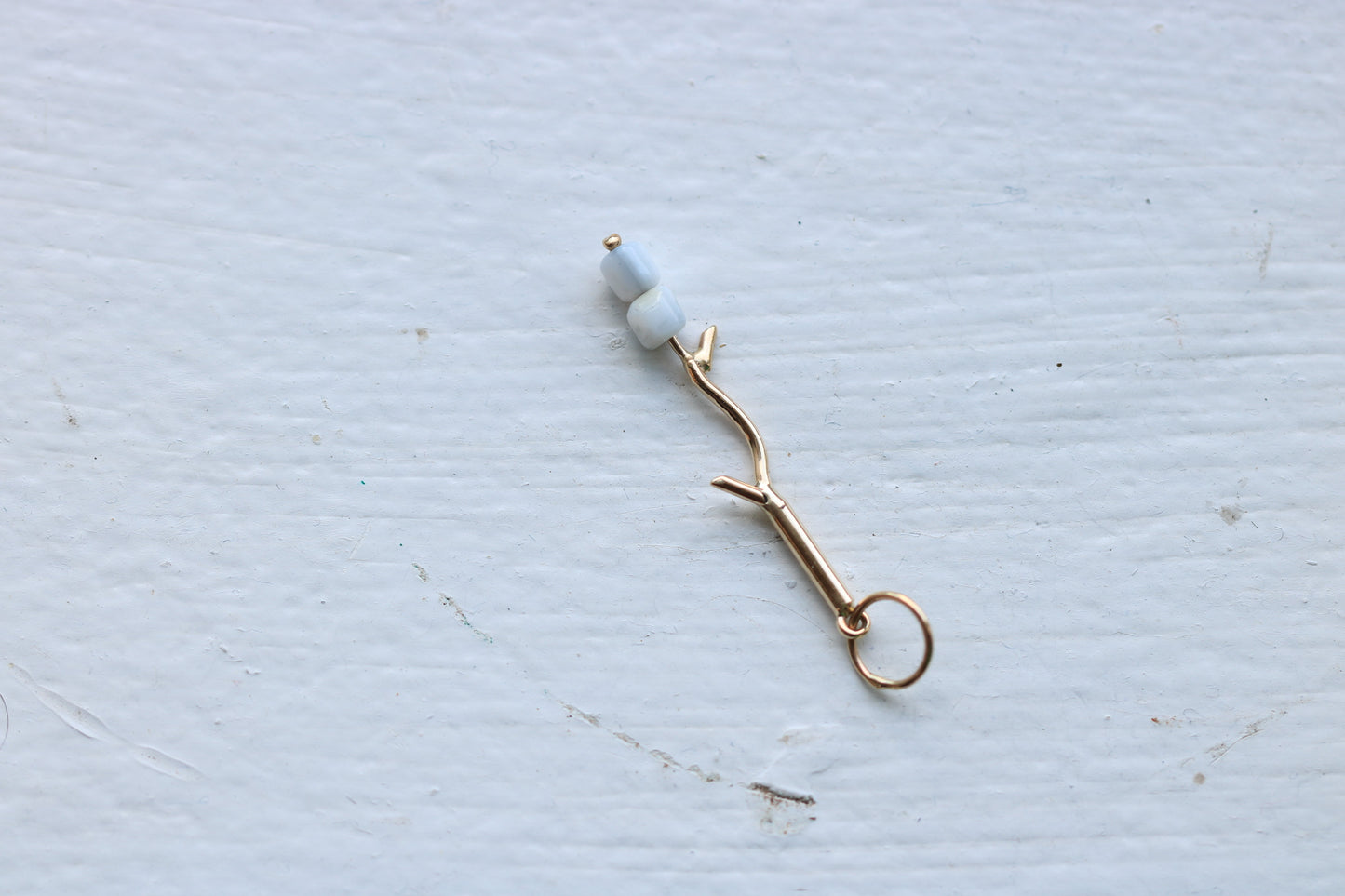 14k yellow gold branch with two mother of pearl marshmallow beads.