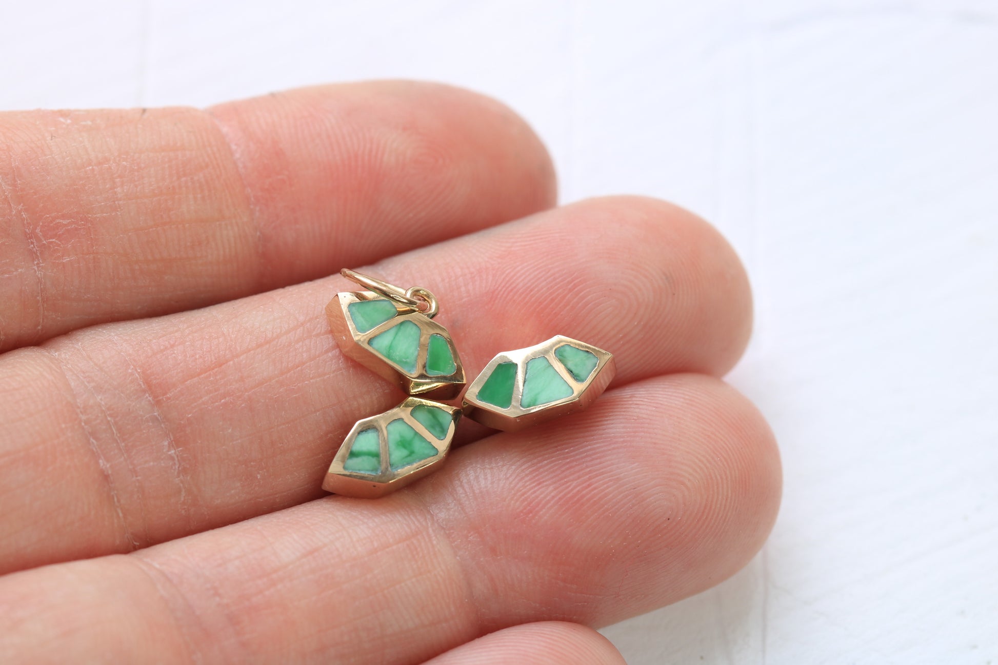 14k gold fan earrings and charm  inlaid with green variscite held in a hand