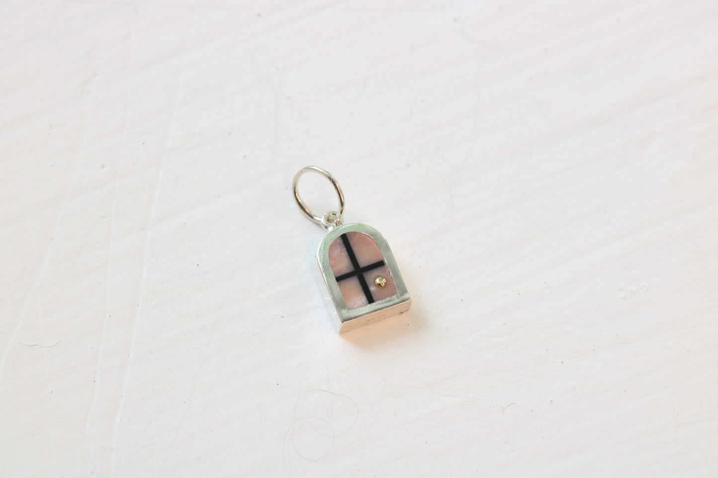silver window charm on table with pink opal inlay and 14k gold sun