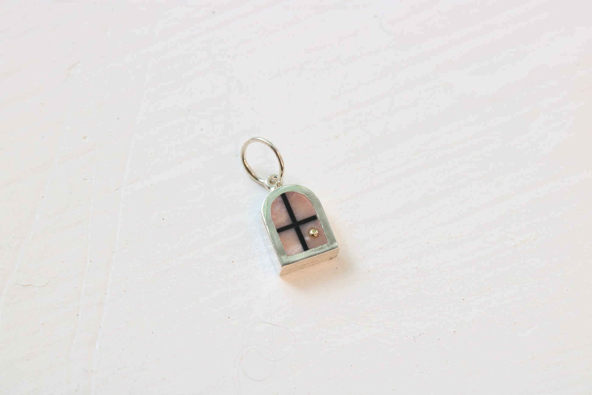 silver window charm on table with pink opal inlay and 14k gold sun